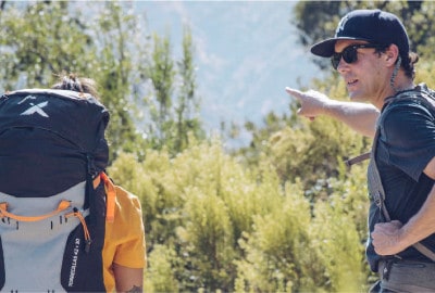 Dos personas cargando mochilas en un sendero de montaña.