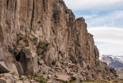 Un hombre está ascendiendo una ruta por la ladera rocosa de una montaña.