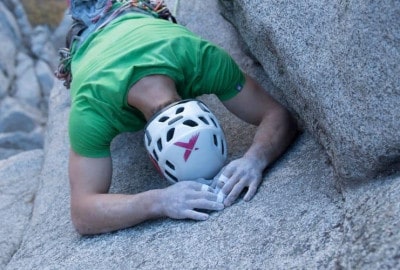 Una persona tirada con cinta adhesiva sobre una roca con un casco puesto.